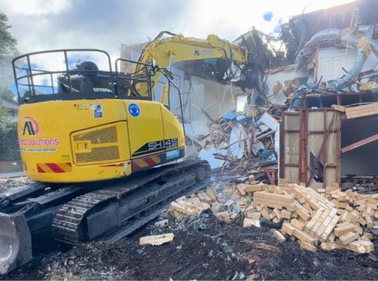 Ademco excavator demolishing a brick house